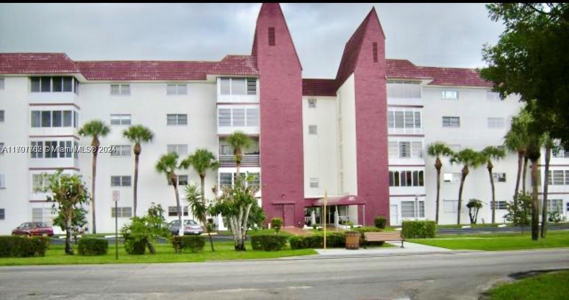 a front view of multi story residential apartment building with yard and traffic signal