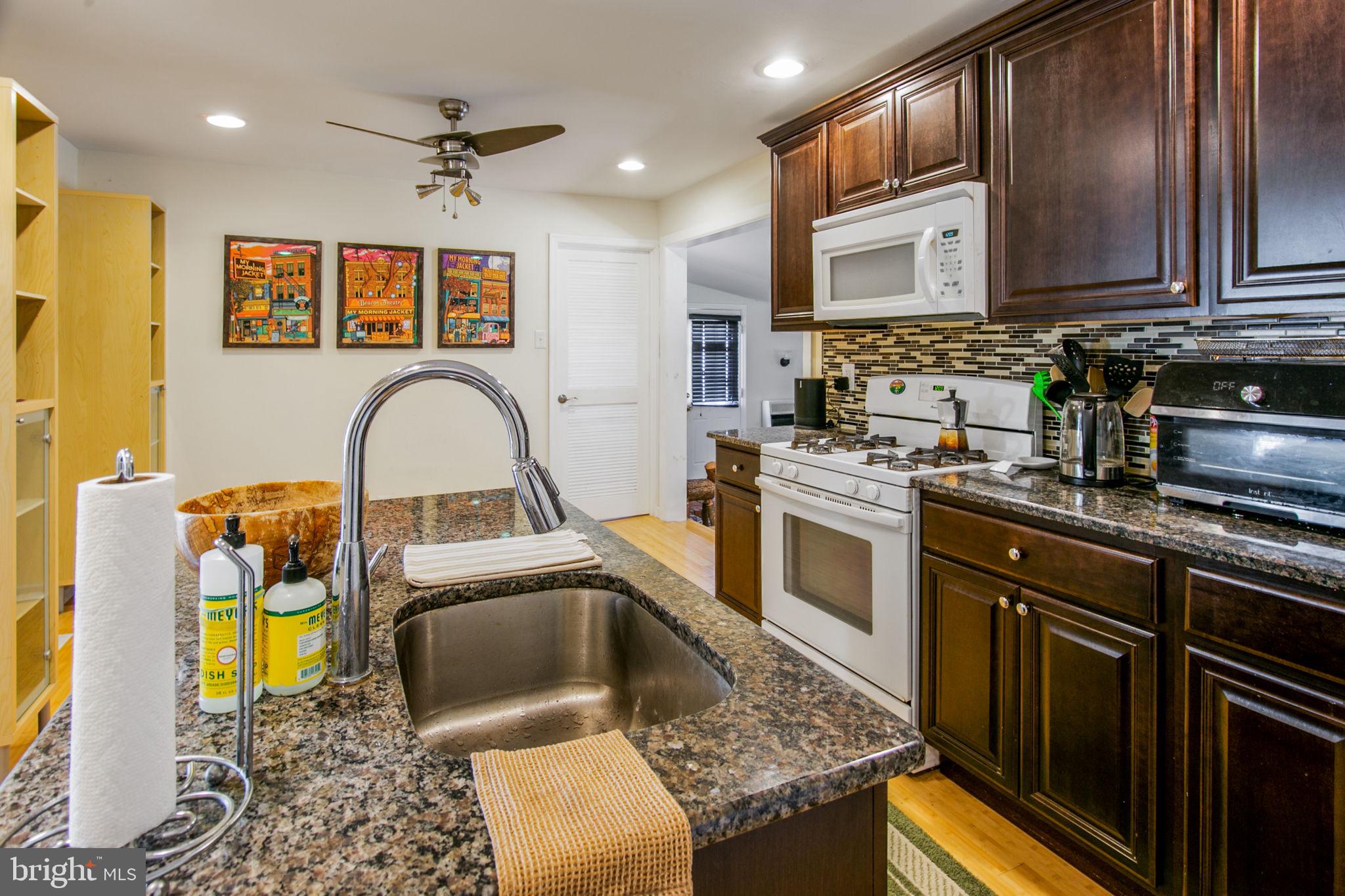 a kitchen with stainless steel appliances granite countertop a stove a sink and a microwave