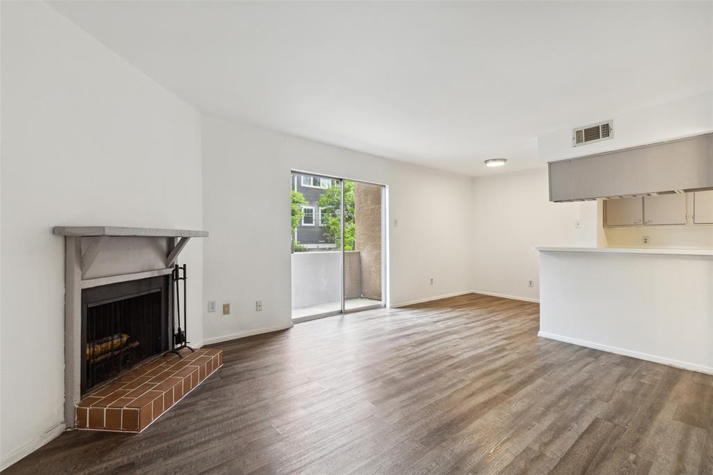 an empty room with wooden floor a fireplace and windows