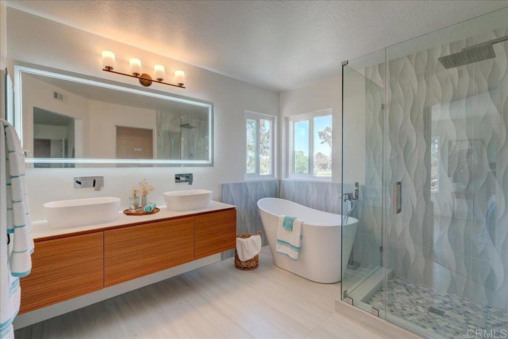 a spacious bathroom with a double vanity sink a large mirror and a bathtub