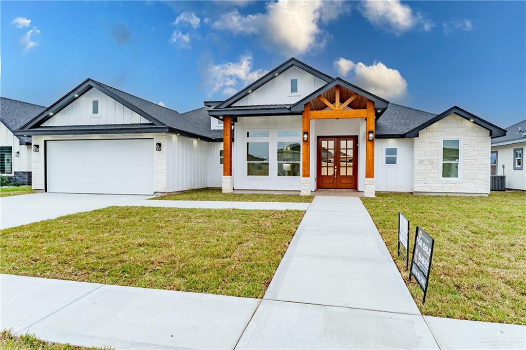 View of front of property with a front lawn, central AC unit, a garage, and french doors