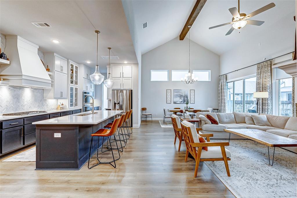 a living room with stainless steel appliances granite countertop dining table wooden floor and a chandelier