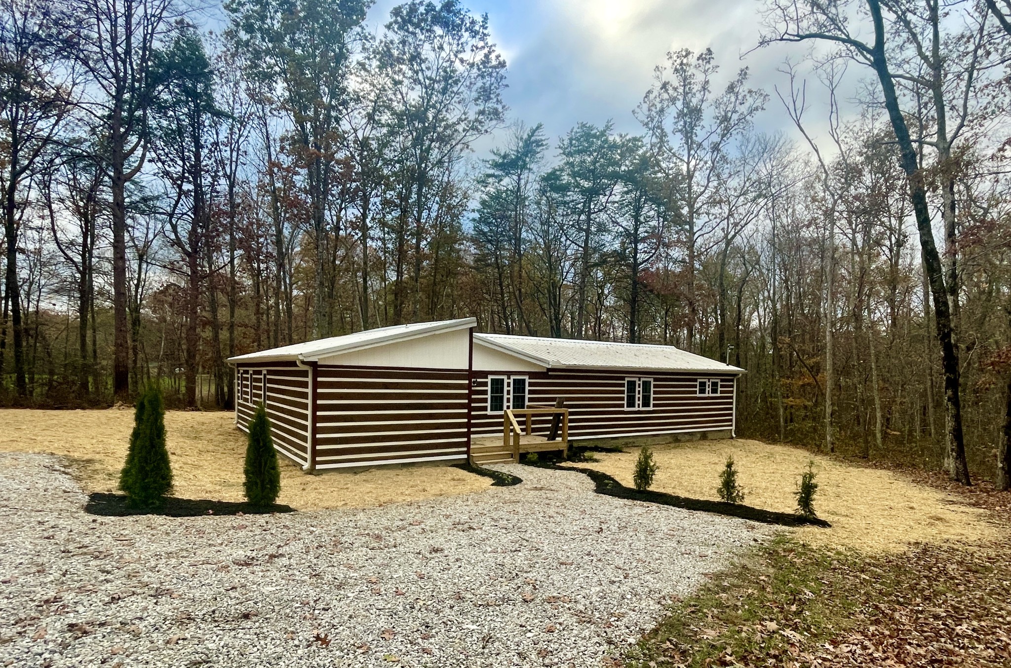 a side view of a house with a yard next to a road