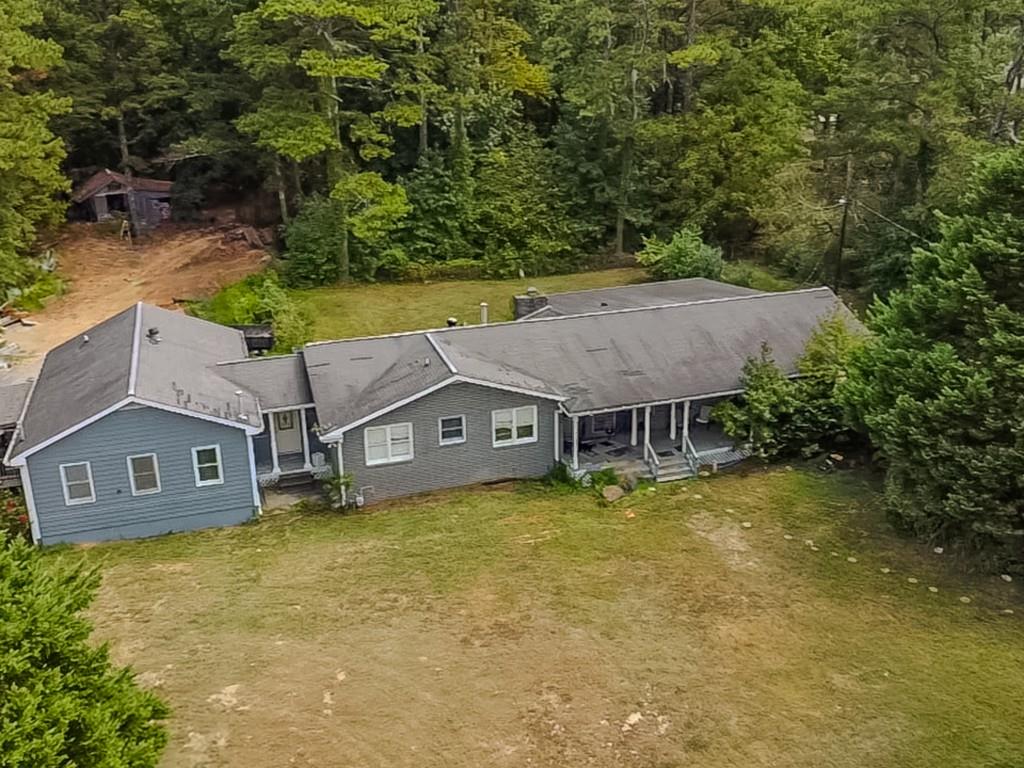 an aerial view of a house with swimming pool and large trees