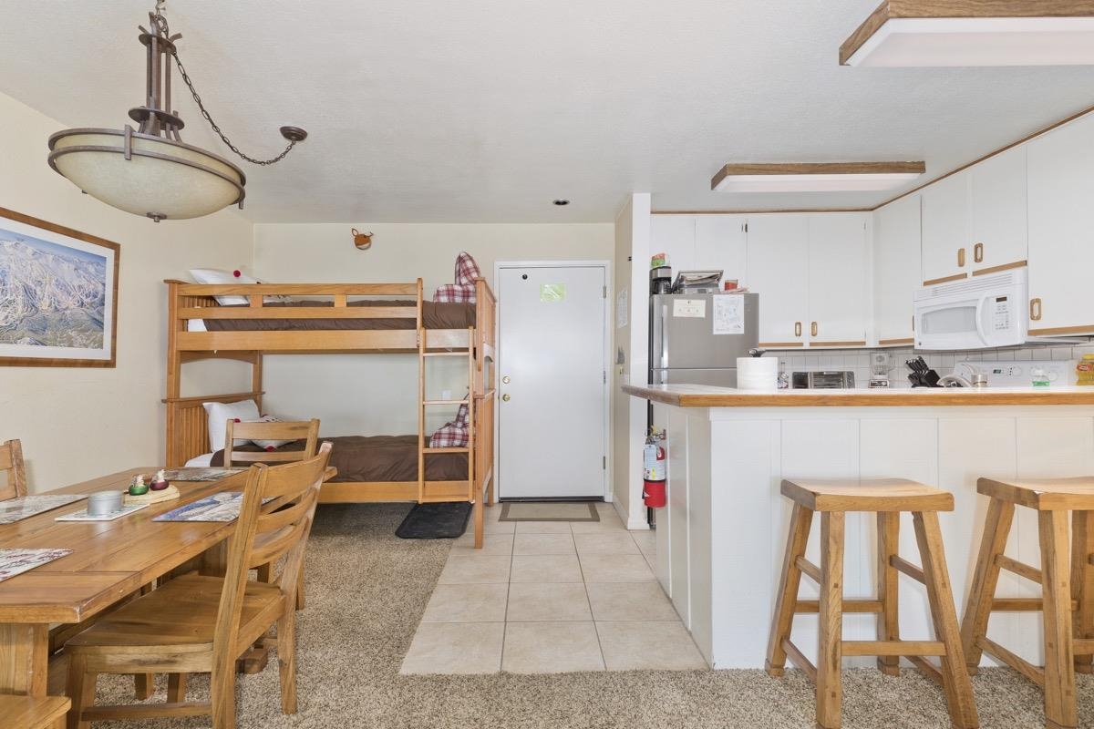 a kitchen with a refrigerator a dining table and chairs in it