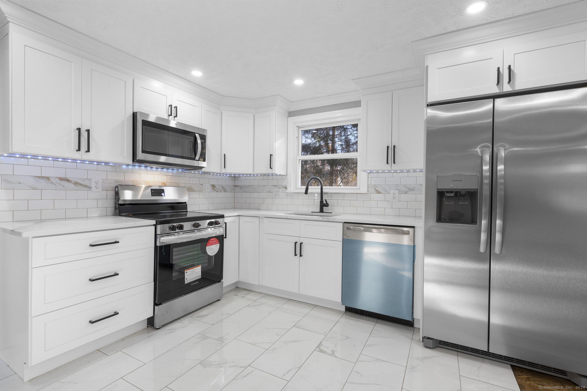 a kitchen with stainless steel appliances granite countertop a refrigerator sink and stove