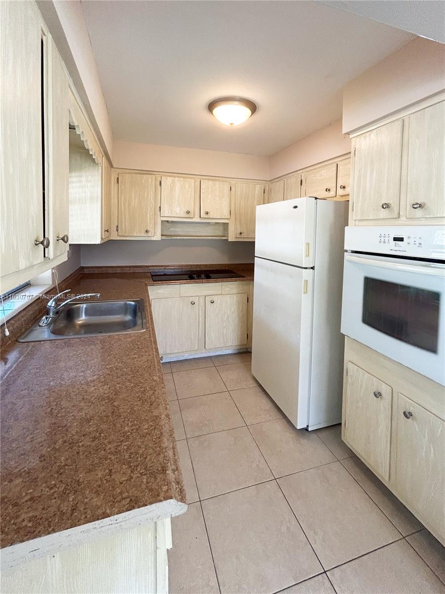 a kitchen with a refrigerator a stove top oven and cabinets