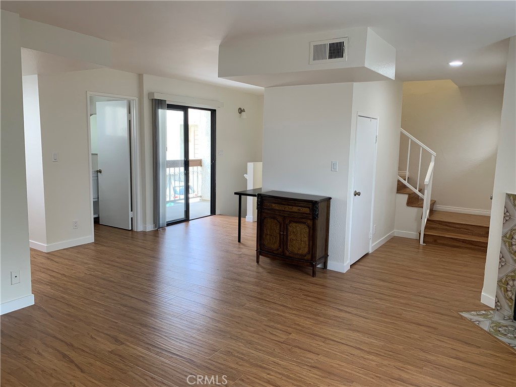 a view of a livingroom with wooden floor and a kitchen space