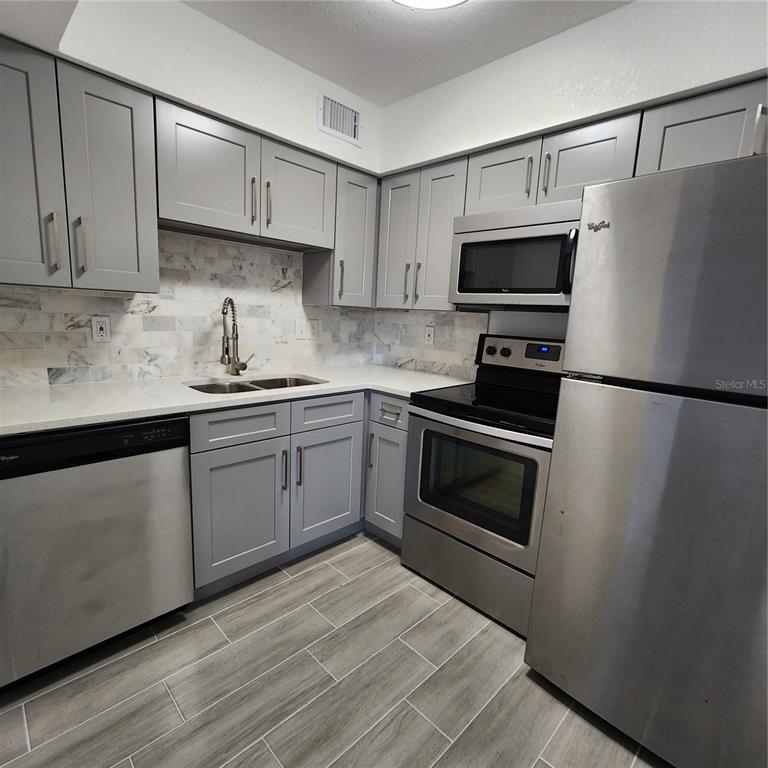 a kitchen with granite countertop a sink stove and refrigerator