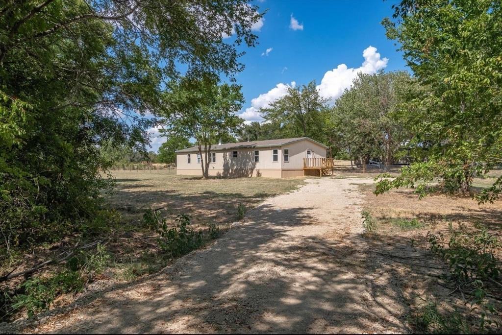 a view of house with outdoor space and trees all around