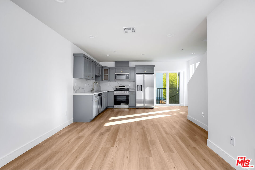 a large kitchen with cabinets wooden floor and stainless steel appliances