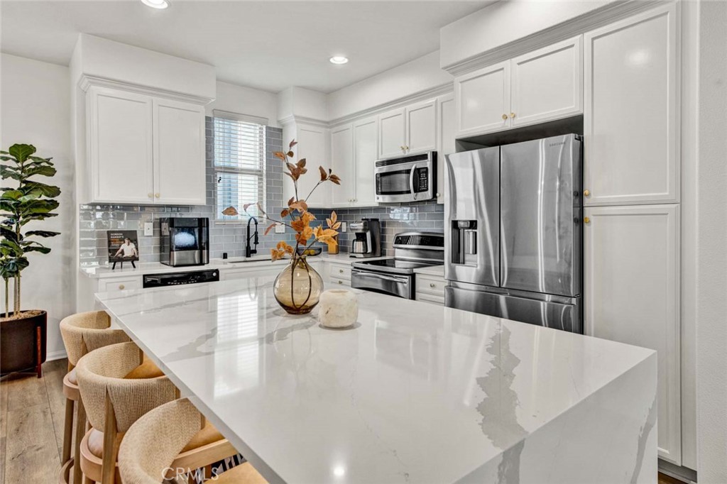 a kitchen with stainless steel appliances granite countertop a sink a refrigerator a stove a dining table and chairs