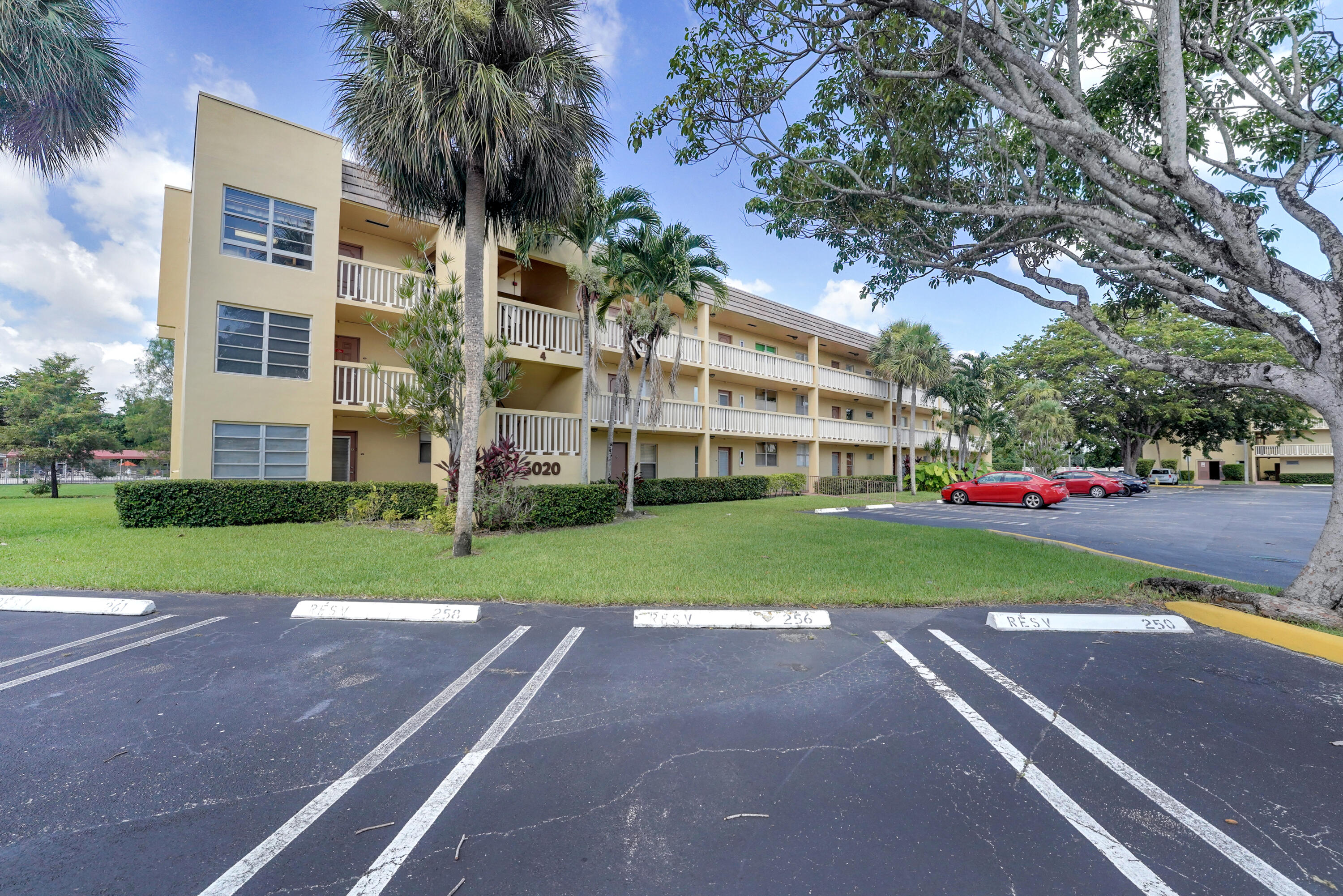 a front view of a building with a garden and trees