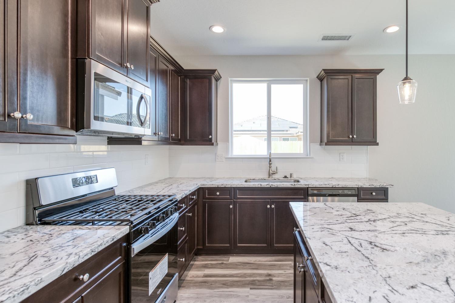 a kitchen with stainless steel appliances granite countertop a sink stove and refrigerator