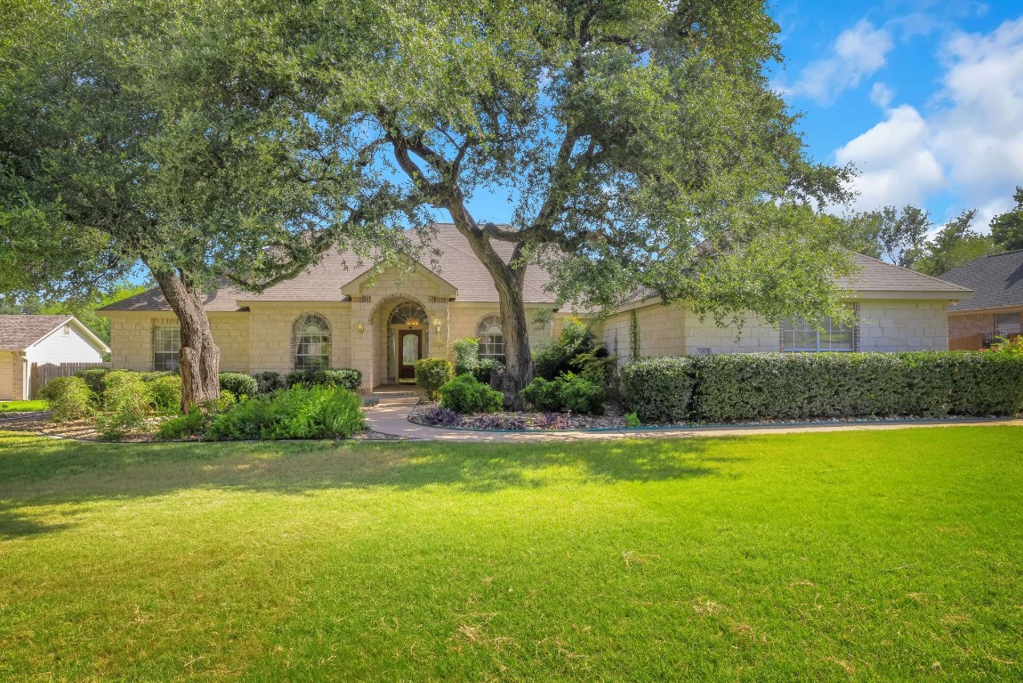 a front view of a house with garden and trees