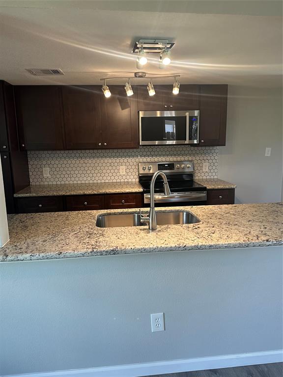 a kitchen with stainless steel appliances granite countertop a sink a stove and a microwave oven