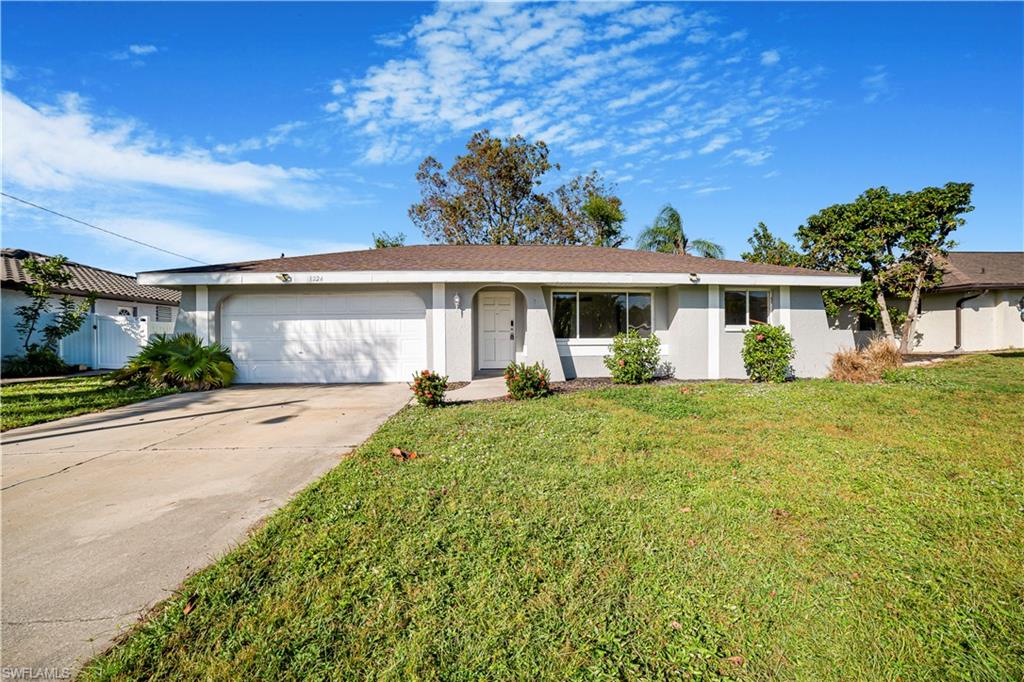 Single story home featuring a garage and a front lawn