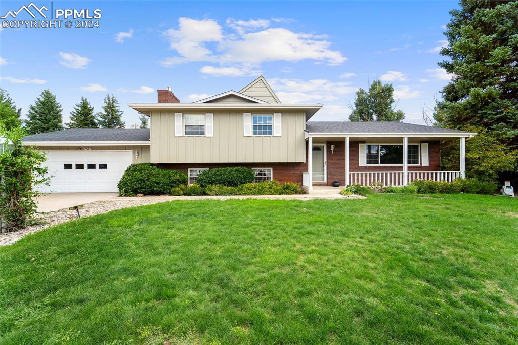 Tri level home with a 2 car garage, workshop in rear, a porch, and front yard