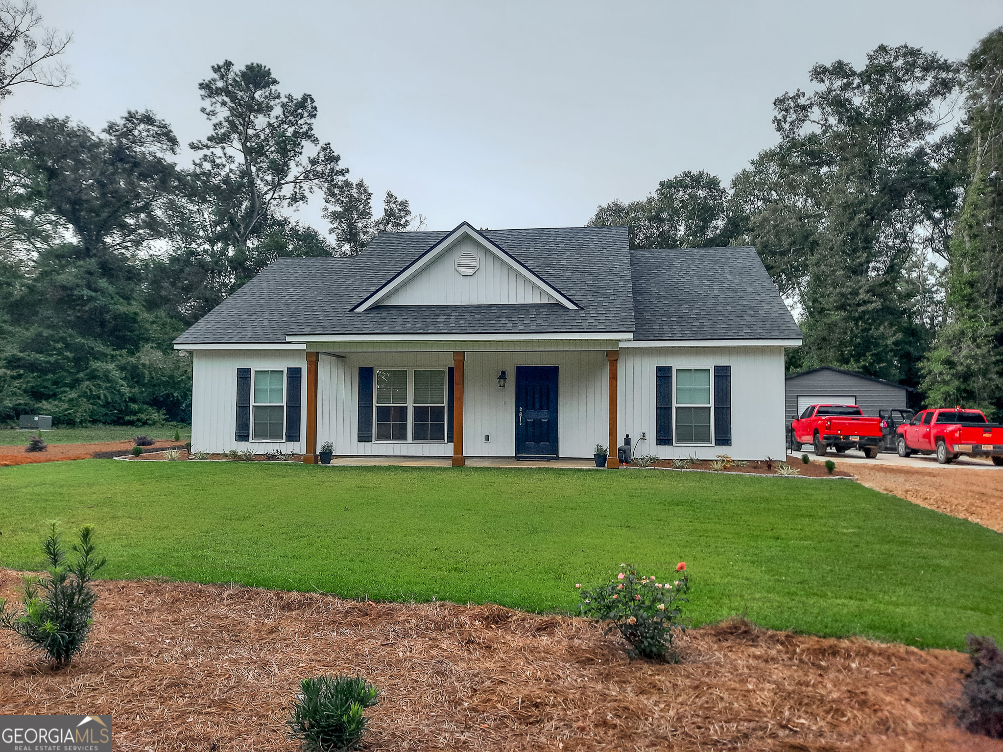 a front view of a house with a garden and trees