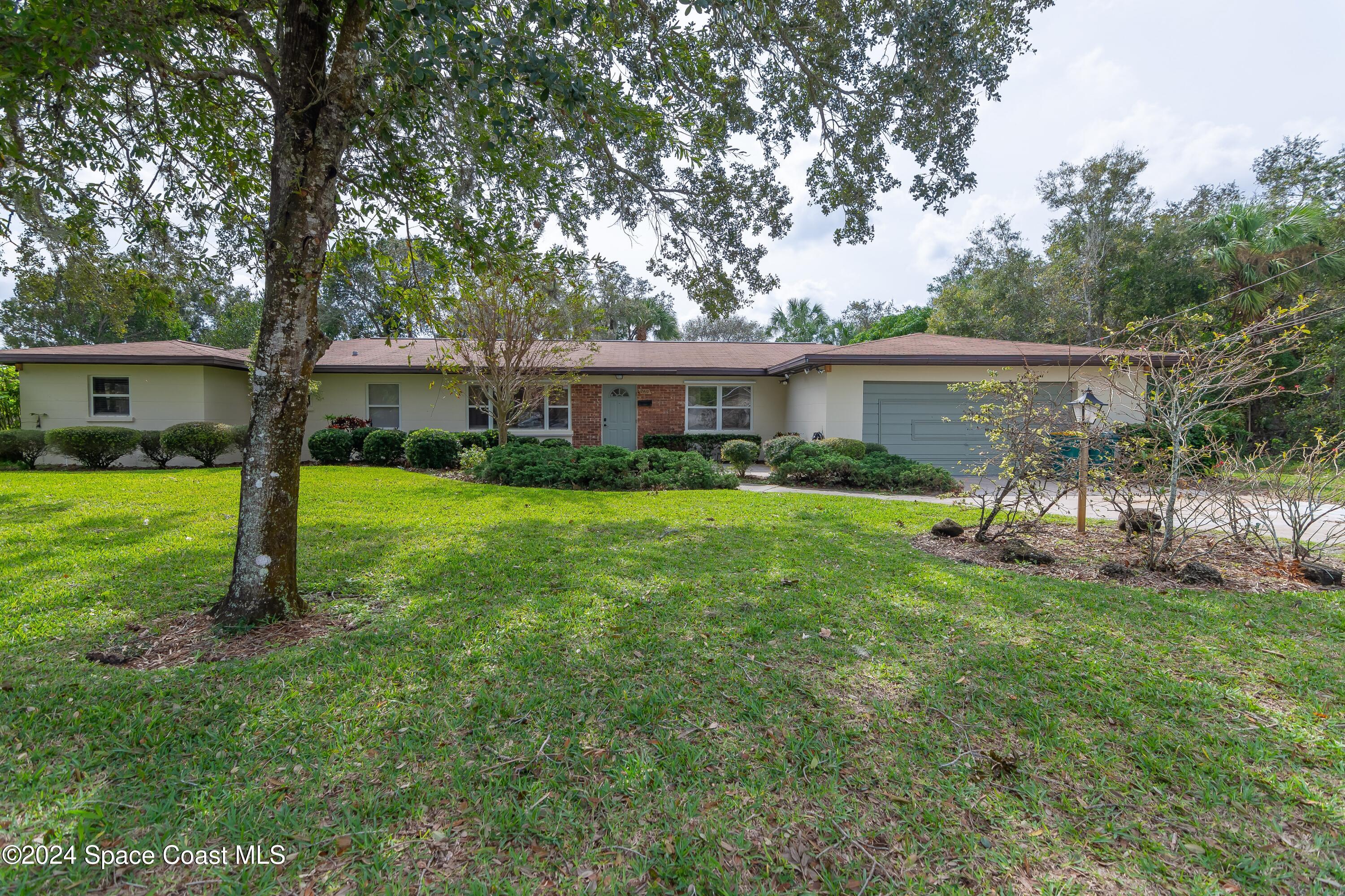 a view of a house with a yard and a tree