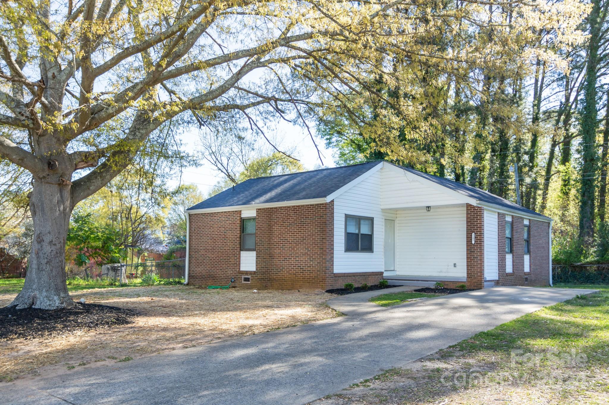 a view of a house with a yard and large tree