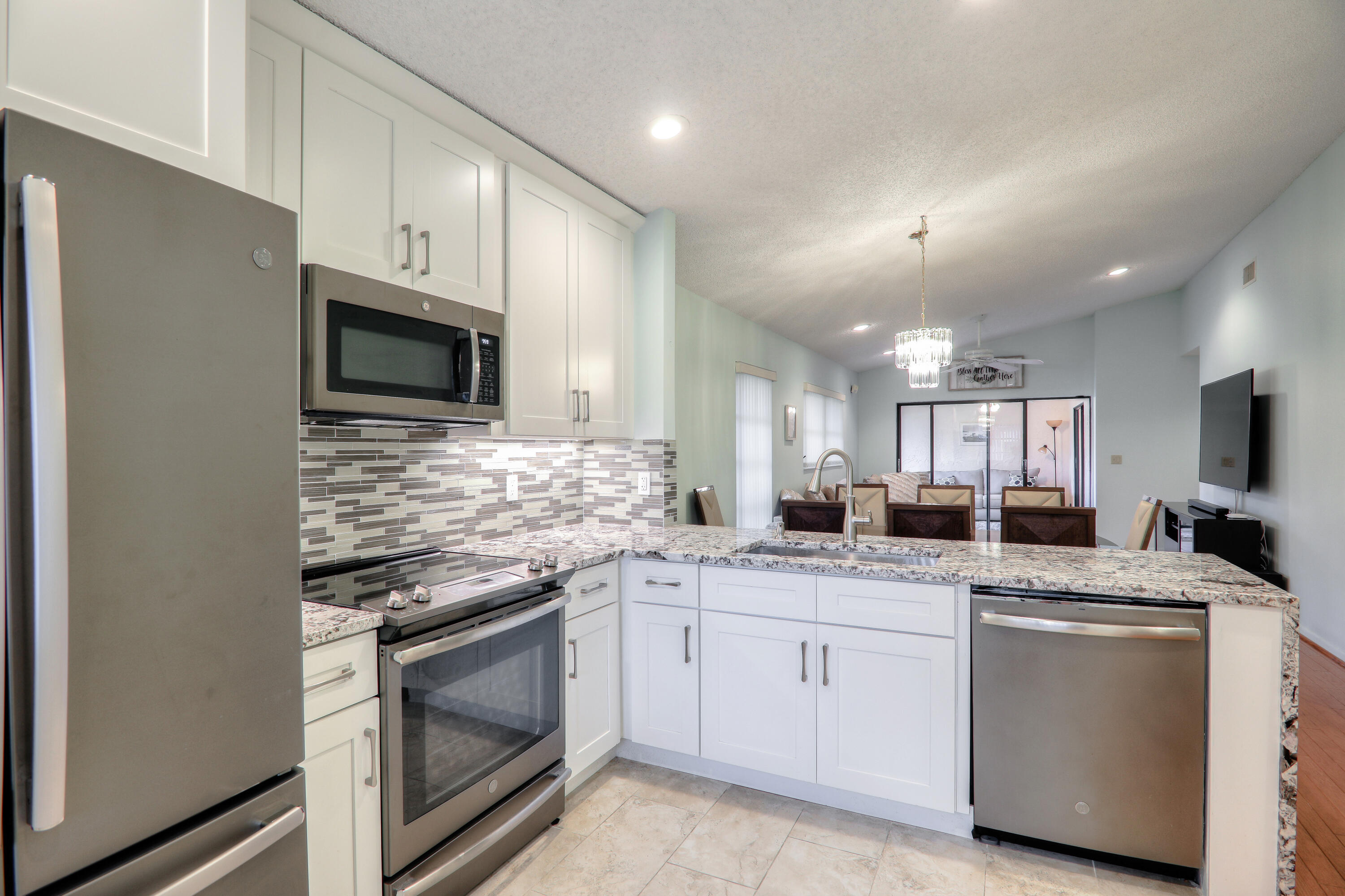 a kitchen with granite countertop a sink stainless steel appliances and white cabinets