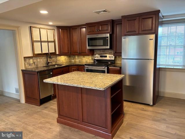 a kitchen with a refrigerator a microwave a sink and cabinets