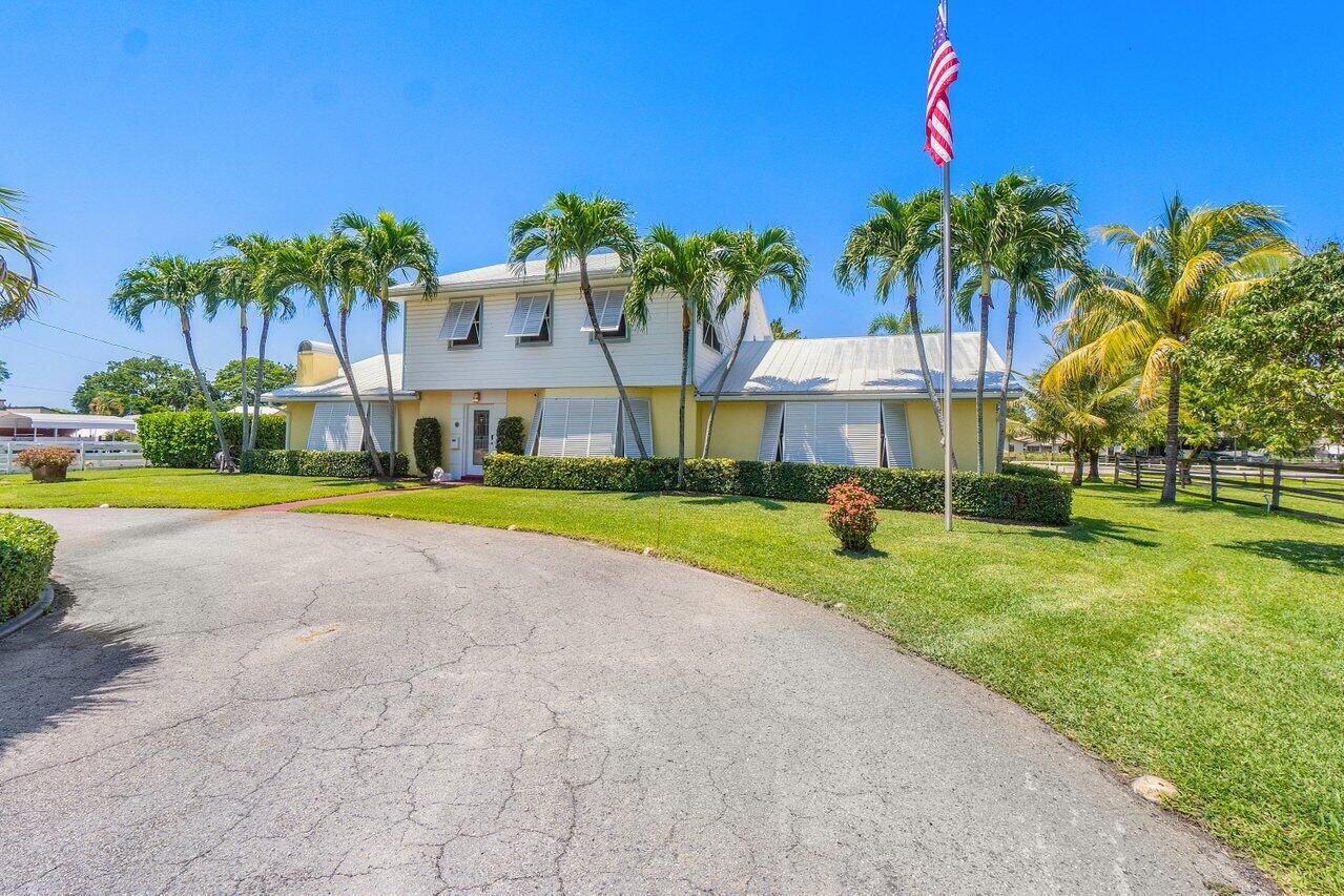 a view of a house with a yard and palm trees