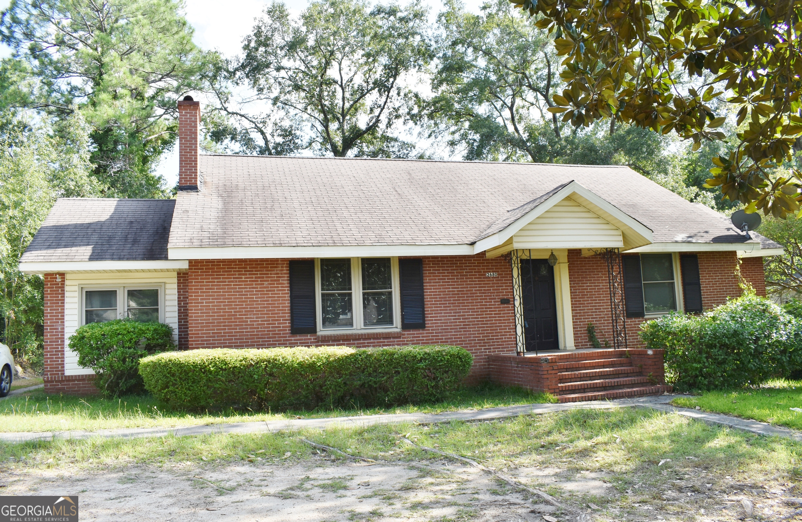 a view of a house with a yard plants and a table and chairs under an umbrella