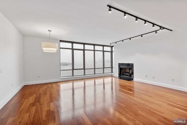 a view of an empty room with wooden floor and fan