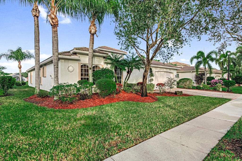 a front view of a house with a garden and palm trees