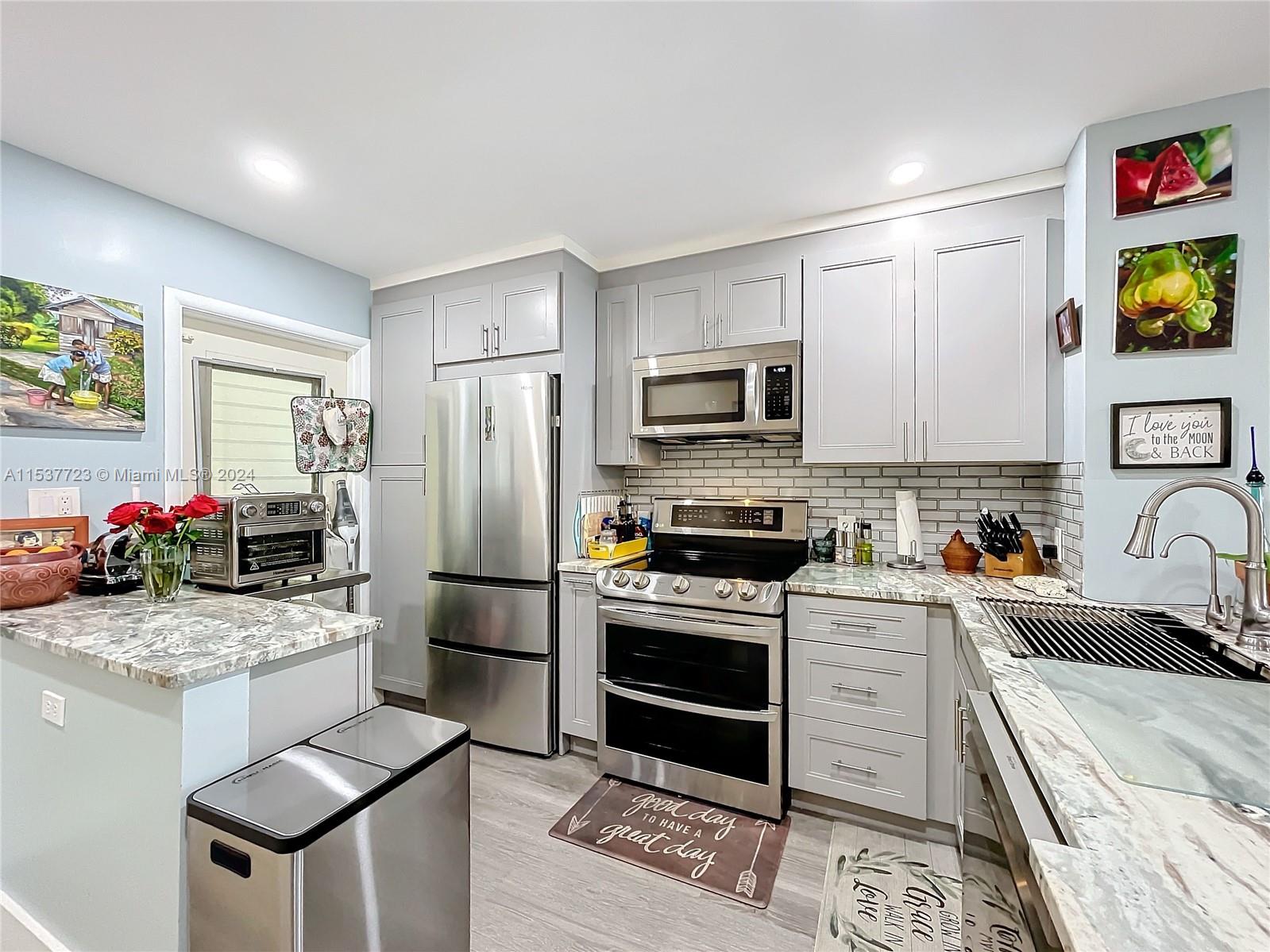 a kitchen with stainless steel appliances kitchen island granite countertop a stove refrigerator and sink