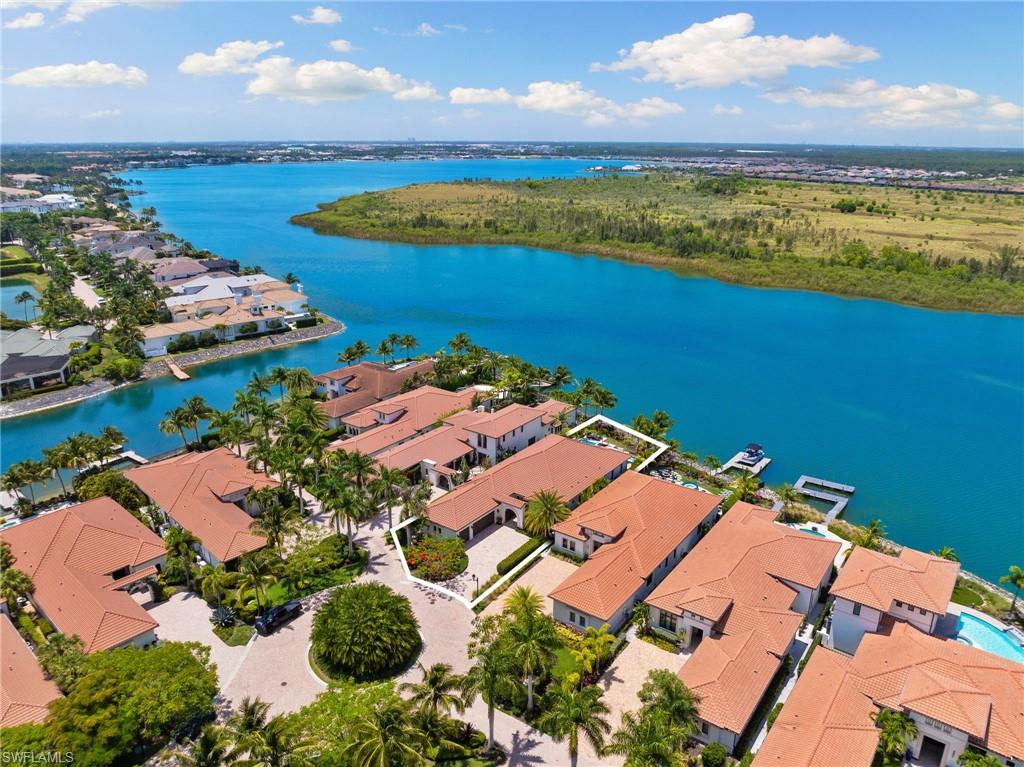 an aerial view of ocean and residential houses with outdoor space