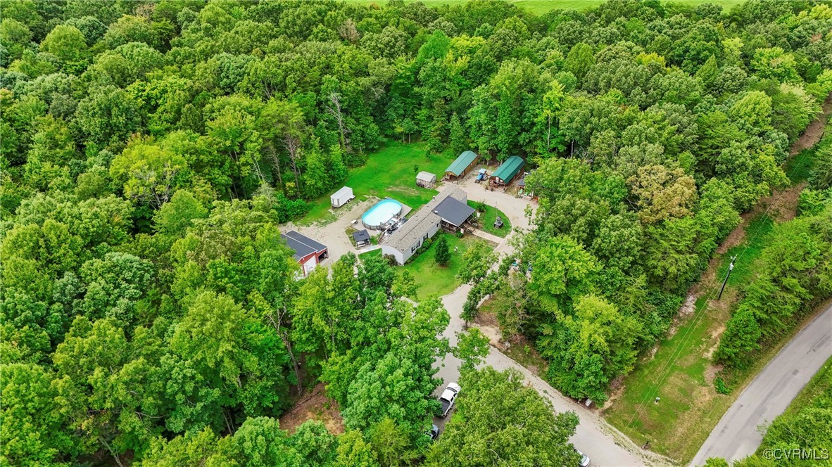 an aerial view of residential house with outdoor space and trees all around