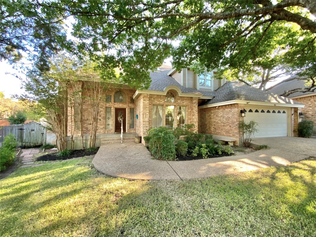 a front view of a house with a garden and tree