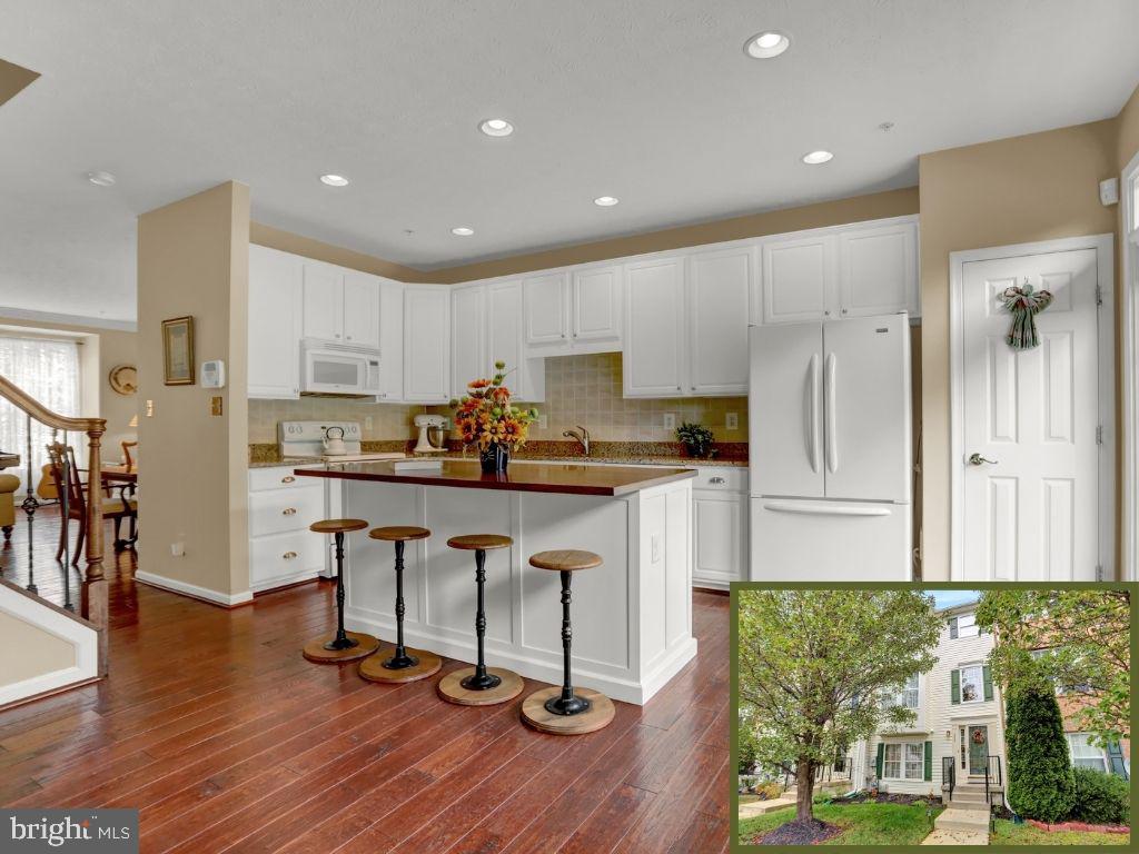 a kitchen with stainless steel appliances granite countertop a refrigerator a stove top oven and a wooden floor