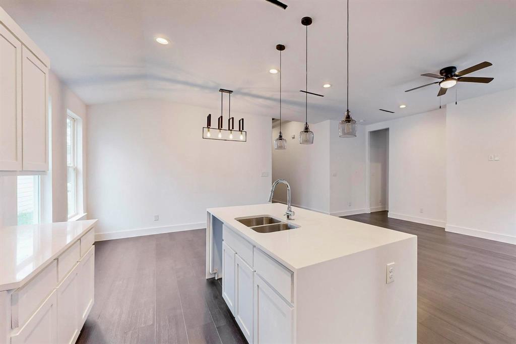 a kitchen that has a sink a stove and wooden floor