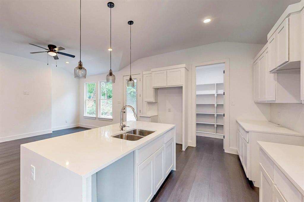 a kitchen with a sink a stove a refrigerator and white cabinets