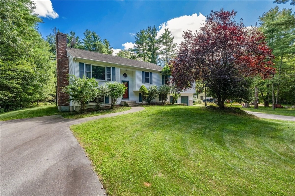 a front view of a house with a garden and trees