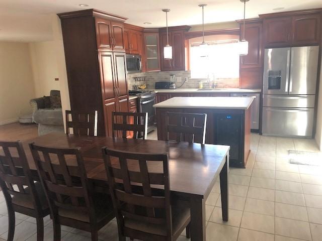 a kitchen with stainless steel appliances granite countertop a dining table chairs refrigerator and sink