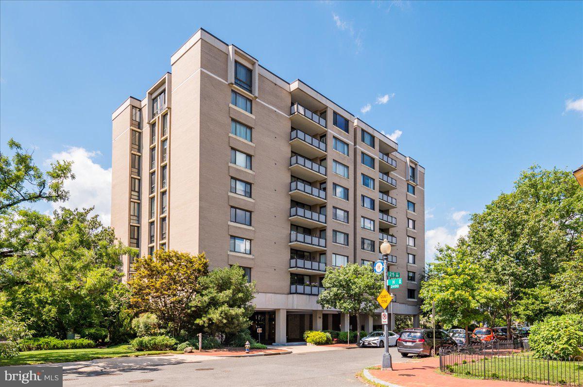 a front view of multi story residential apartment building with yard and parking space