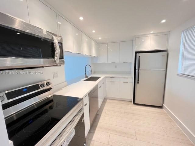 a kitchen with a sink stainless steel appliances and white cabinets