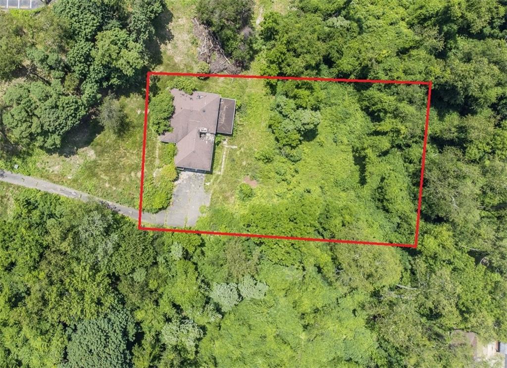 an aerial view of residential house with outdoor space and trees all around