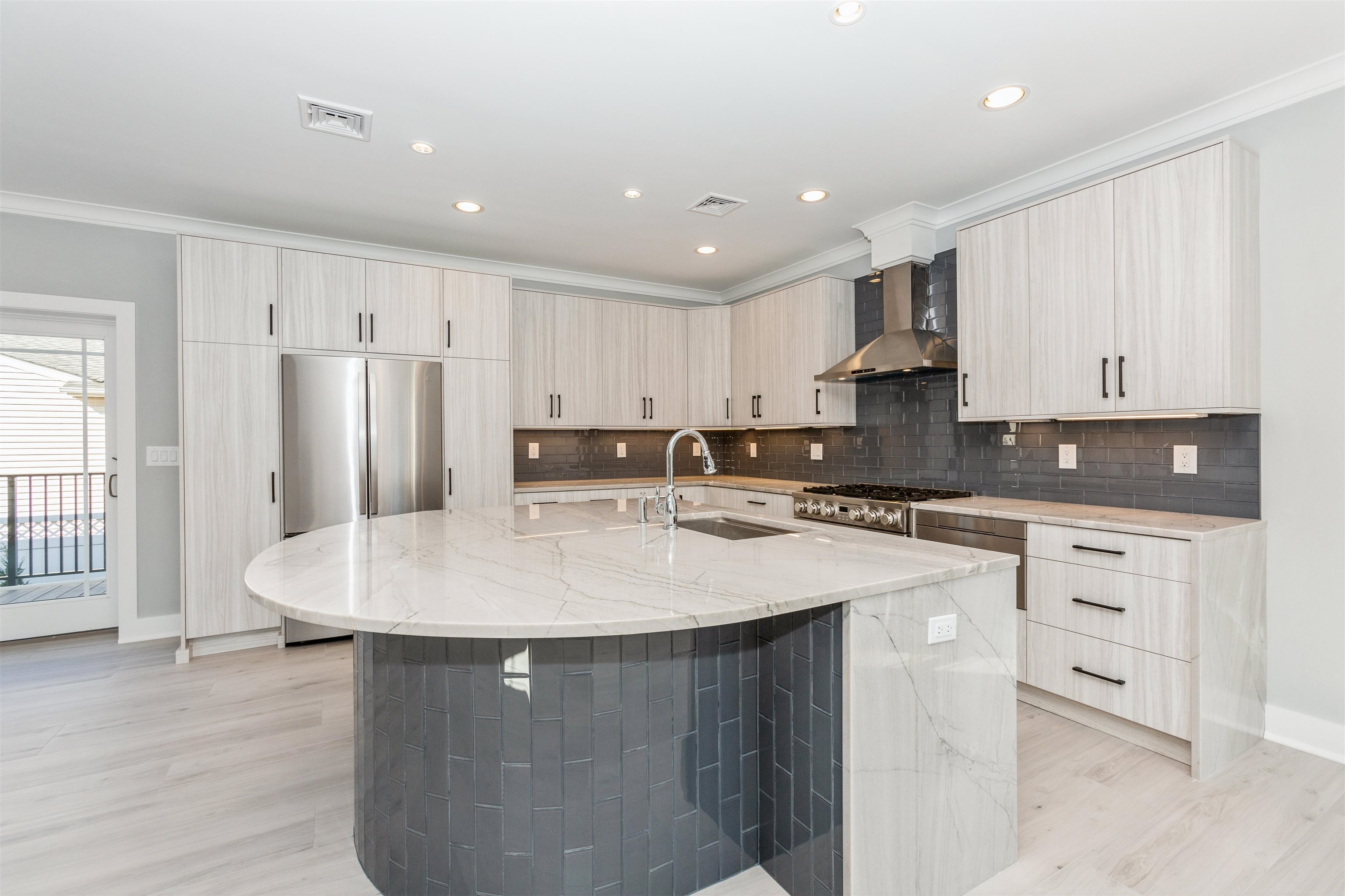 a kitchen with stainless steel appliances granite countertop a sink a stove a refrigerator and white cabinets