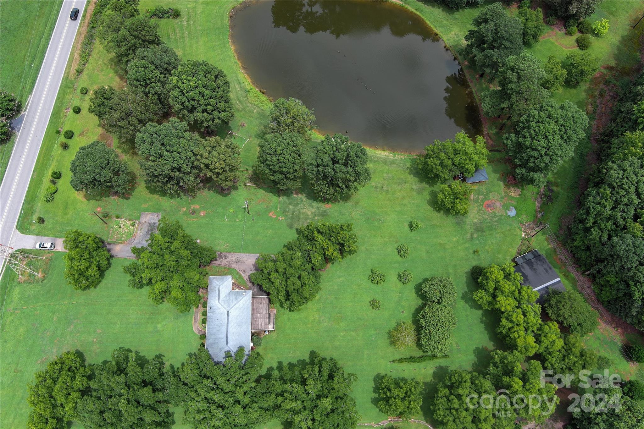 an aerial view of residential house with outdoor space and trees all around