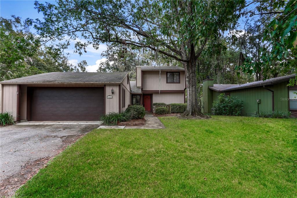 a view of a house with a yard plants and large tree