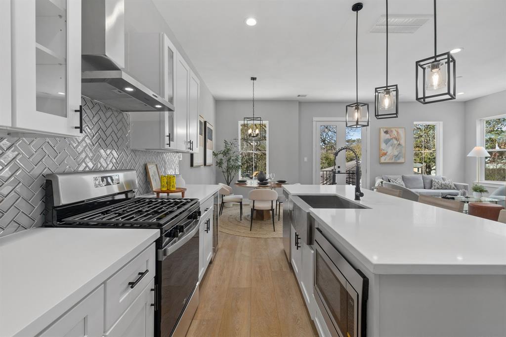 a kitchen with stainless steel appliances a stove a sink dishwasher and white cabinets with wooden floor