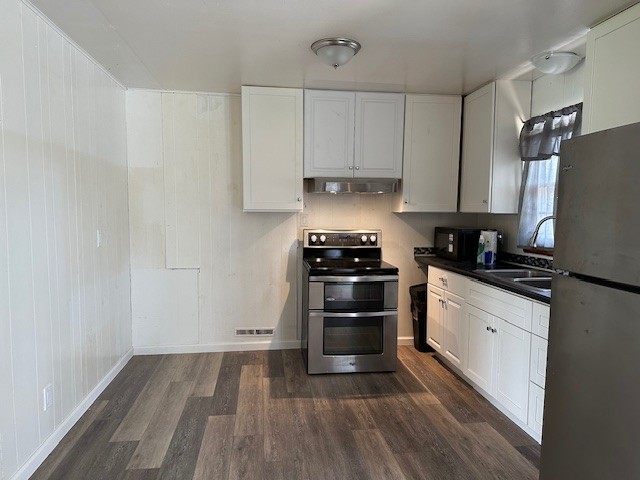 a kitchen with granite countertop a refrigerator stove and white cabinets