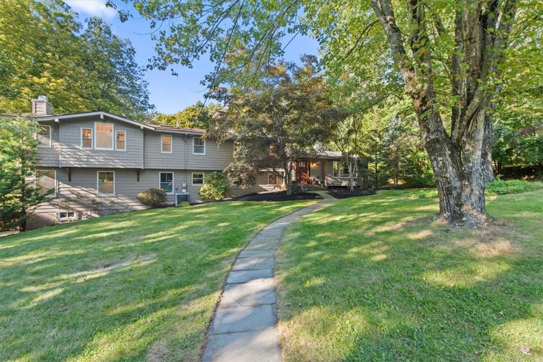 View of front of home with a front yard and central AC