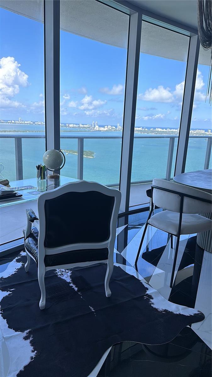 a living room with a table chairs and a floor to ceiling window